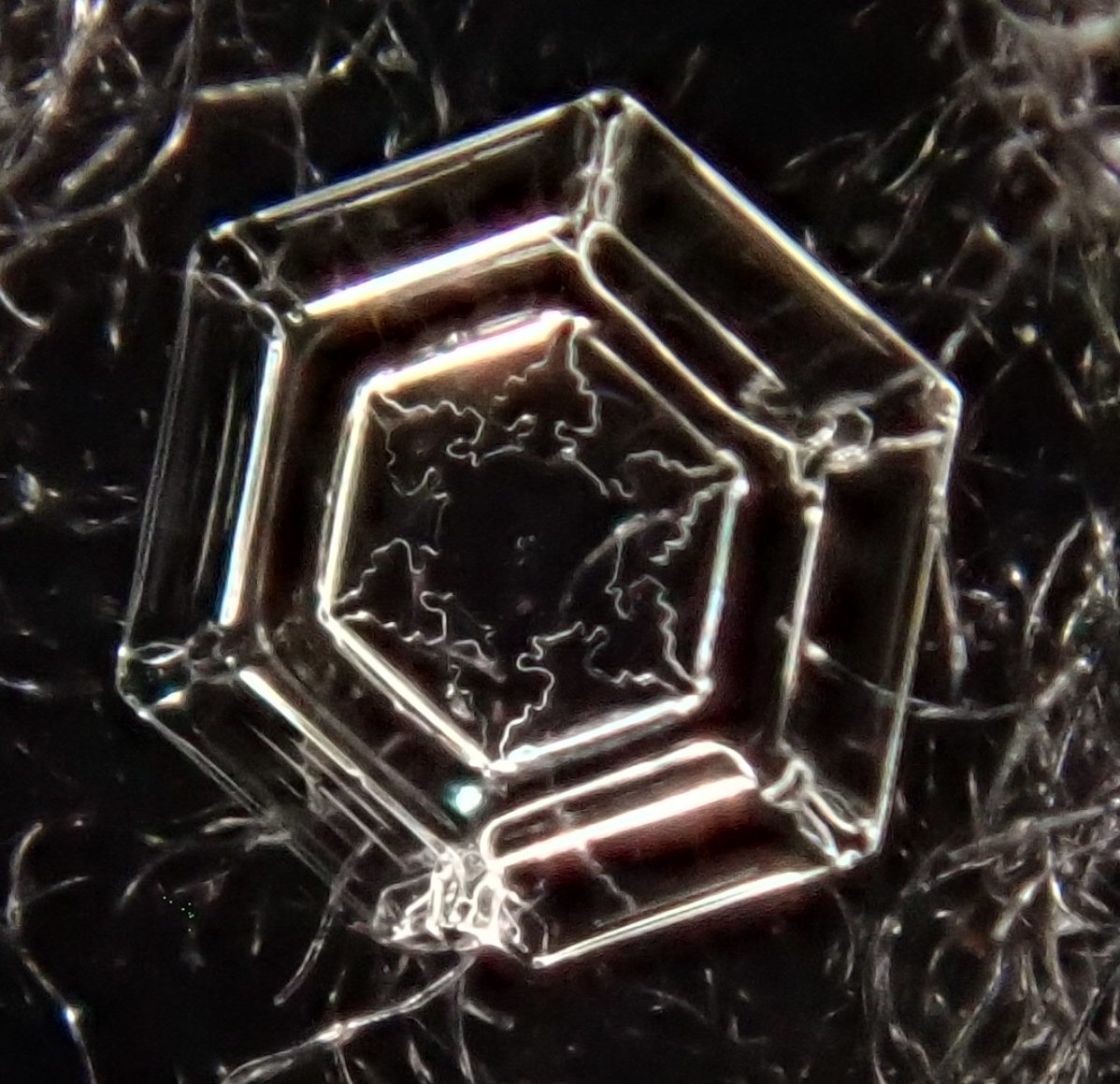 small plate snowflake with hexagonal shape etched into its surface